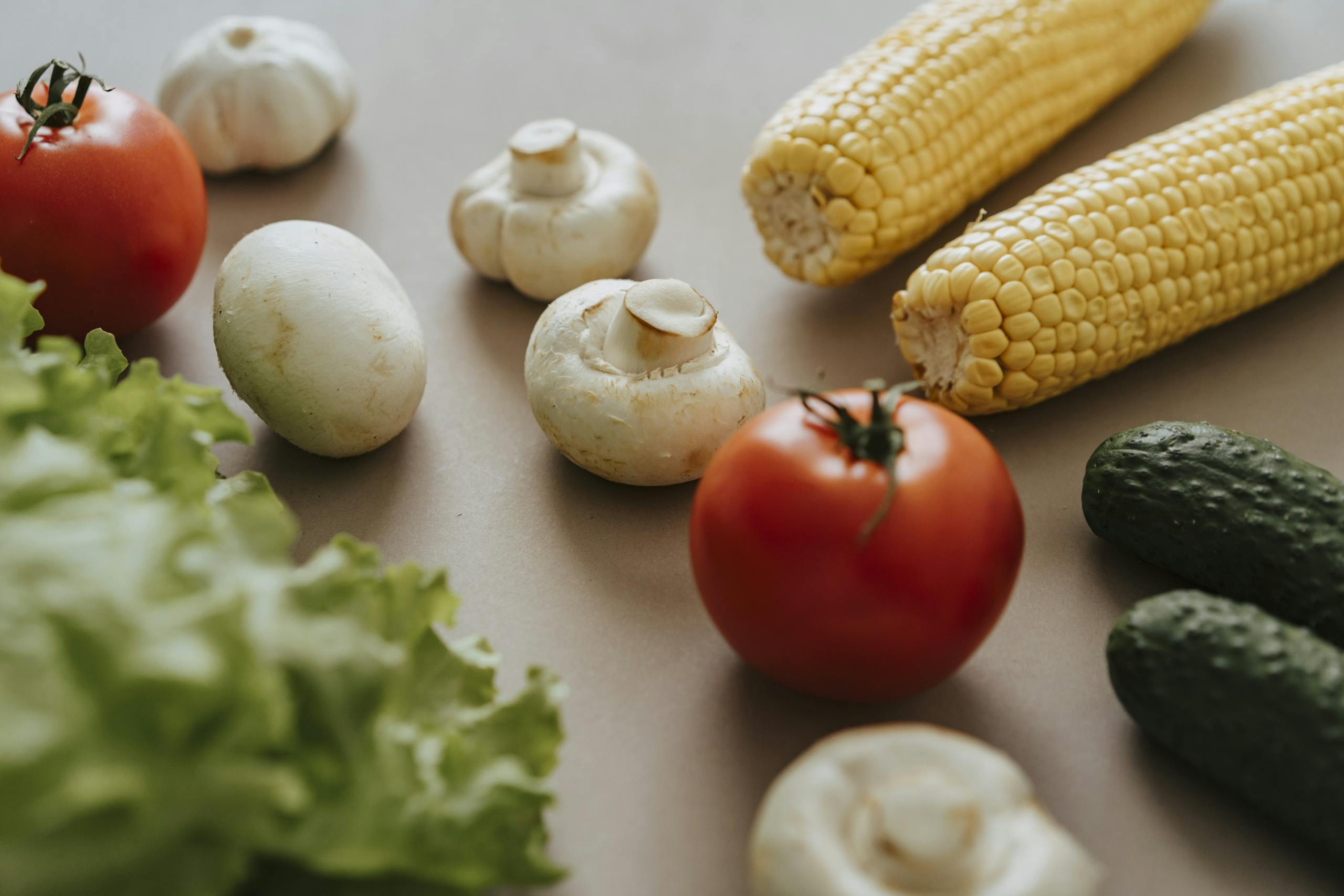 A variety of colorful fresh vegetables displayed on a neutral surface, showcasing their natural beauty.
